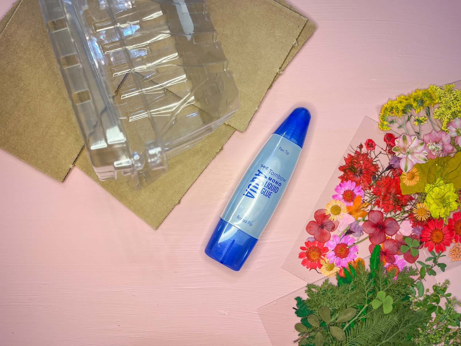 Supplies you'll need to make DIY Dried Flower Bookmarks from Recycled Packaging, cardboard or plastic packaging, Tombow MONO Aqua Liquid Glue, & Dried Flowers