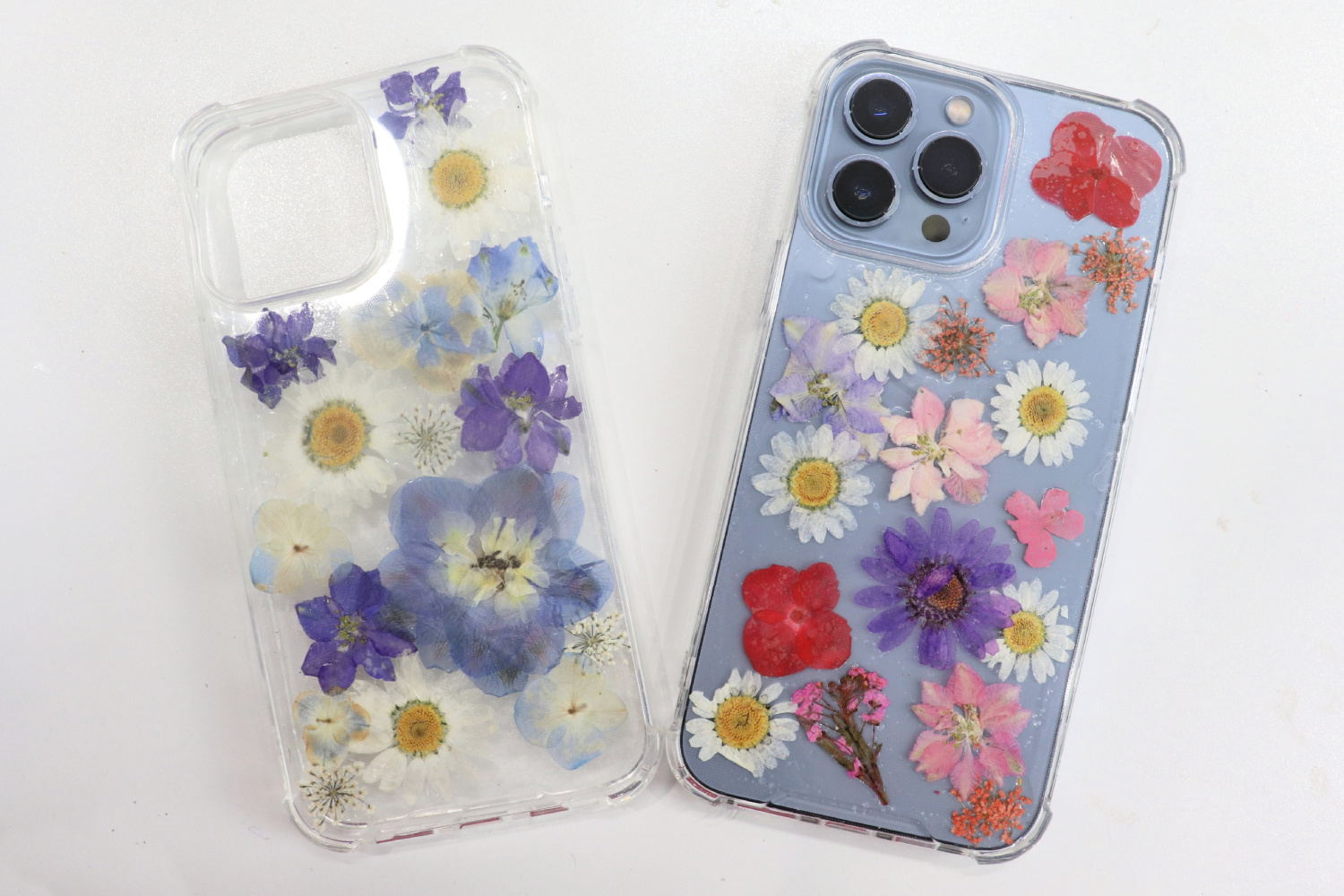 Image contains two clear phone cases decorated with pressed flowers and Tombow MONO Aqua Liquid Glue.