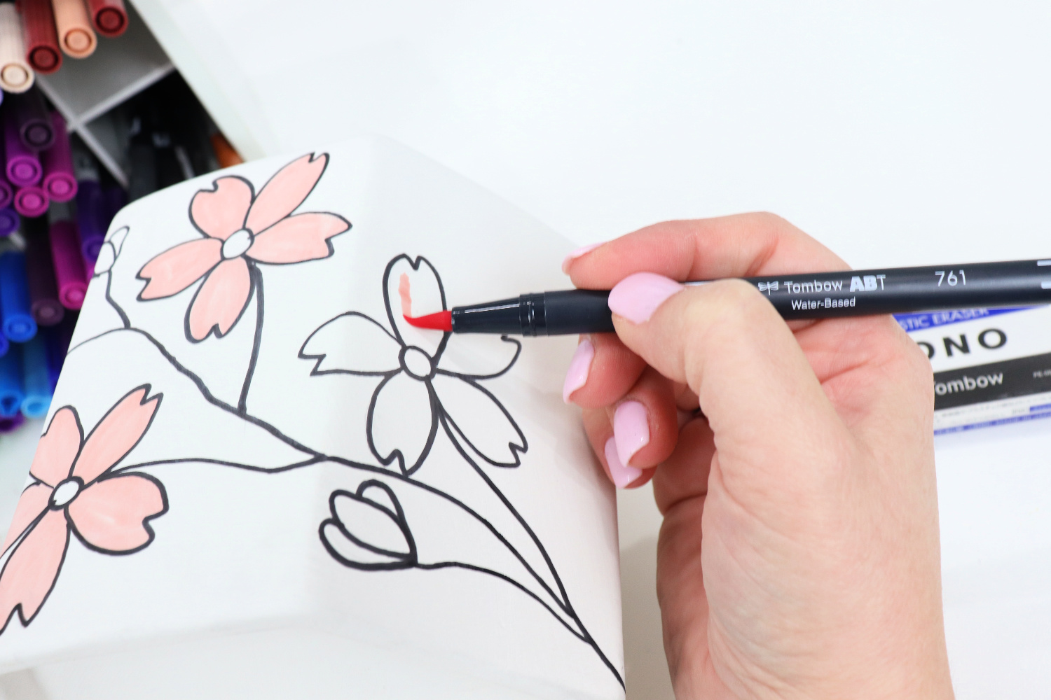 Image contains Amy’s hand using a pink Dual Brush Pen to color in the flowers on the planter.