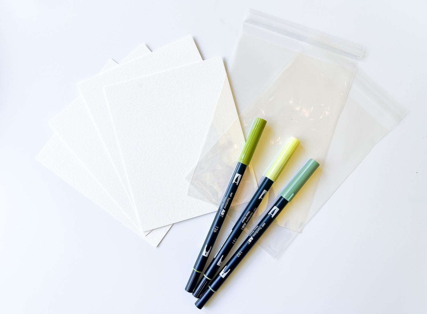Supplies you'll need to make DIY S'mores Packs: @tombowusa Dual Brush Pen Landscape 10-pack, watercolor paper, cellophane bags, MONO Air Touch Adhesive Runner, & a Paintbrush