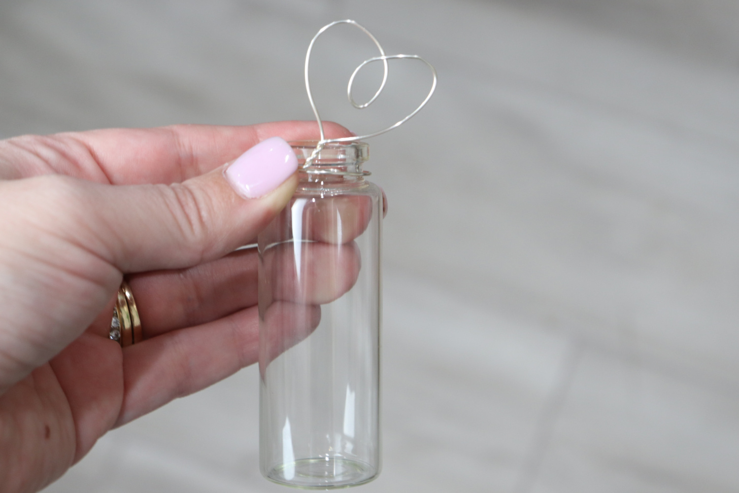 Image contains Amy’s hand wrapping the wire heart around the mouth of a tiny jar.