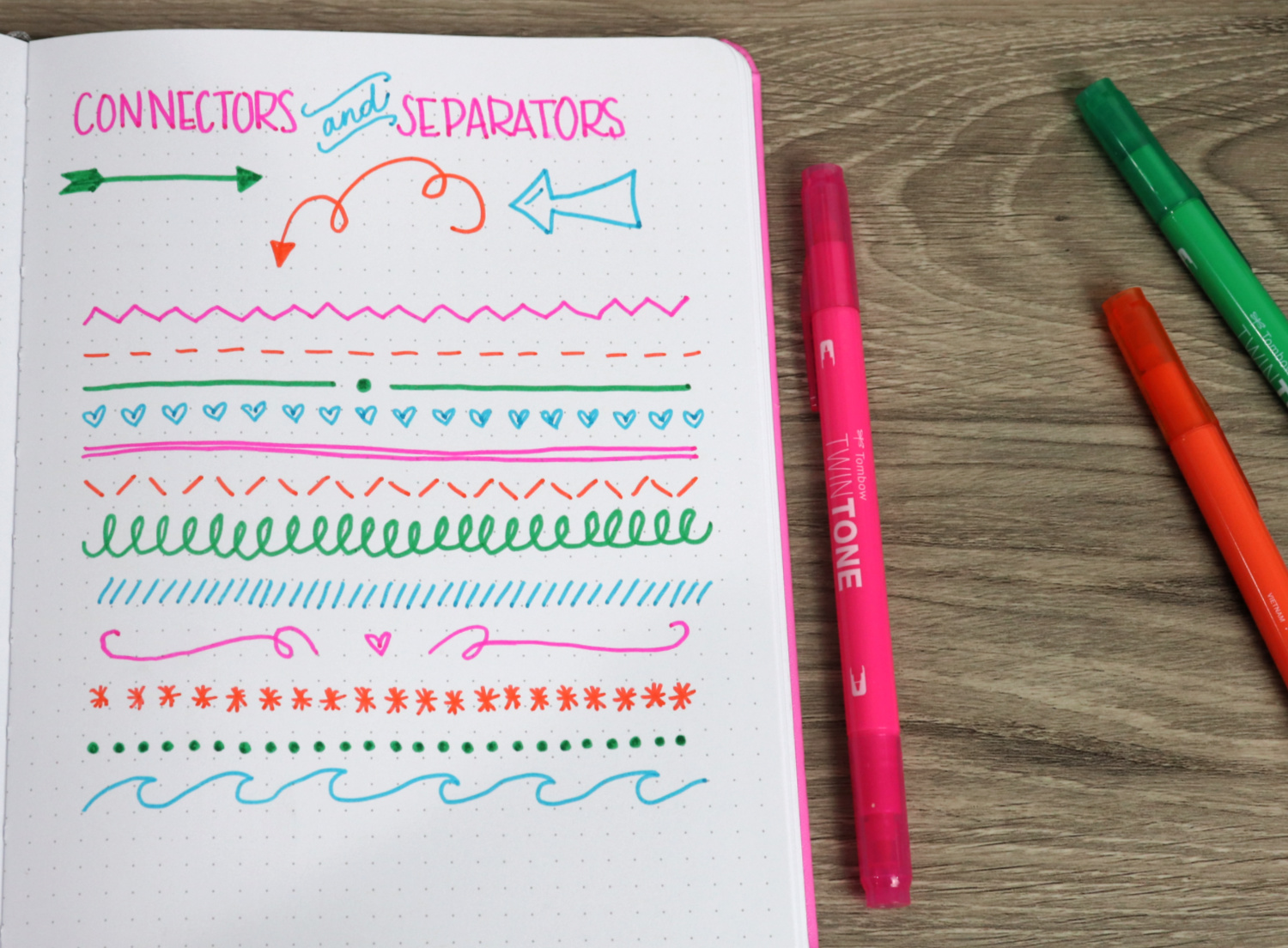 Image contains an open notebook page with a variety of connectors and separators drawn on it. Three markers sit off to the side on a wooden desktop.