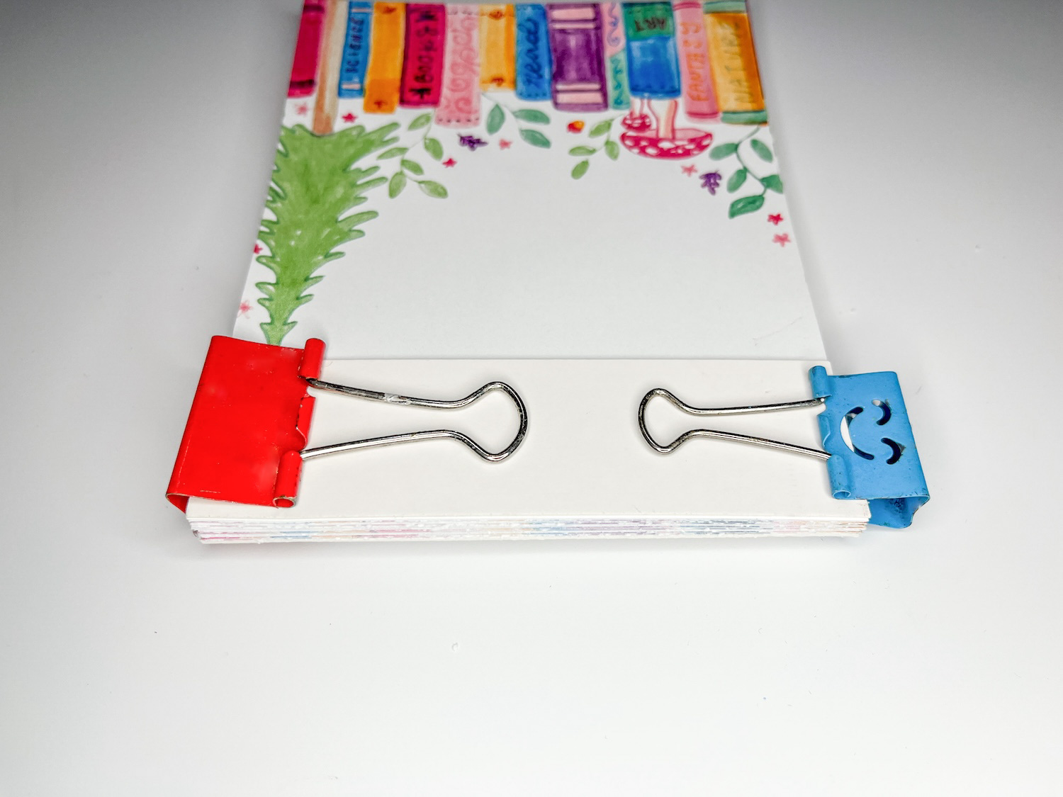 Use binder clips to clamp all of your notepad sheets together