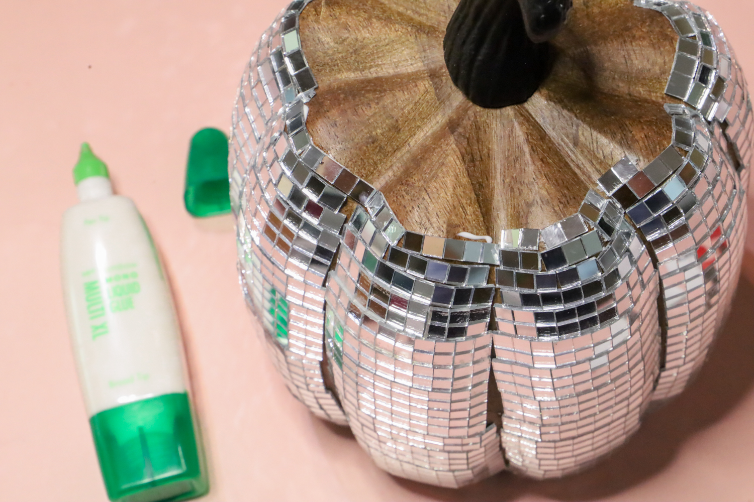 To make a Disco Ball Pumpkin, continue adhering disco tiles all the way around your faux pumpkin