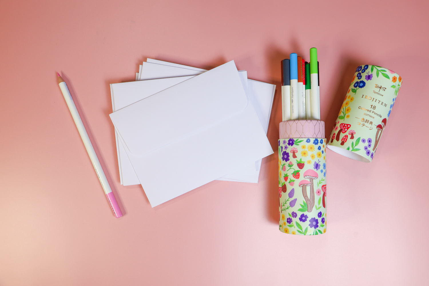 White envelopes and Tombow Irojiten Desk Cup, Cottage laying on a pink background