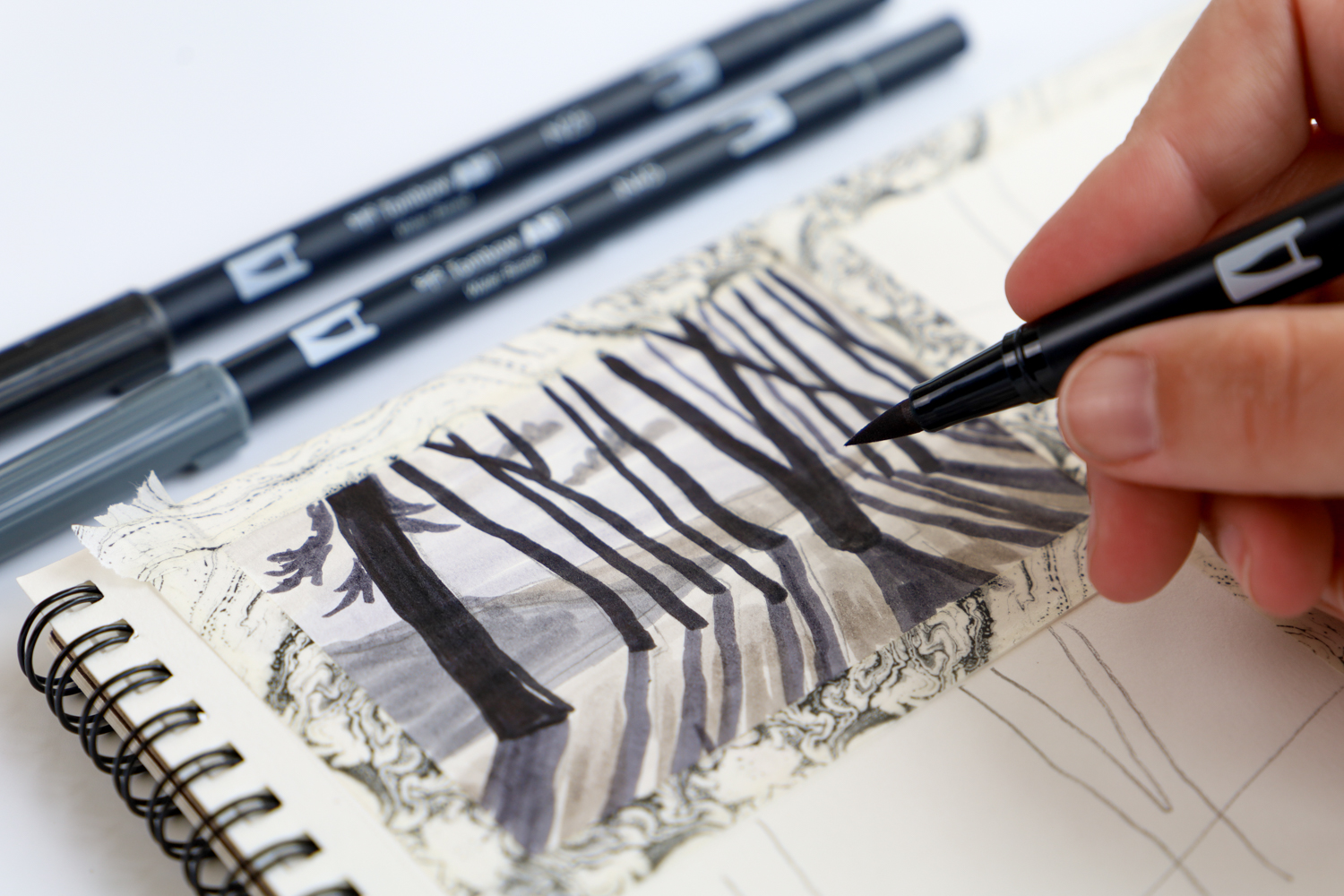 Hand holding Tombow Dual Brush Pen, creating a value study of a forest illustration