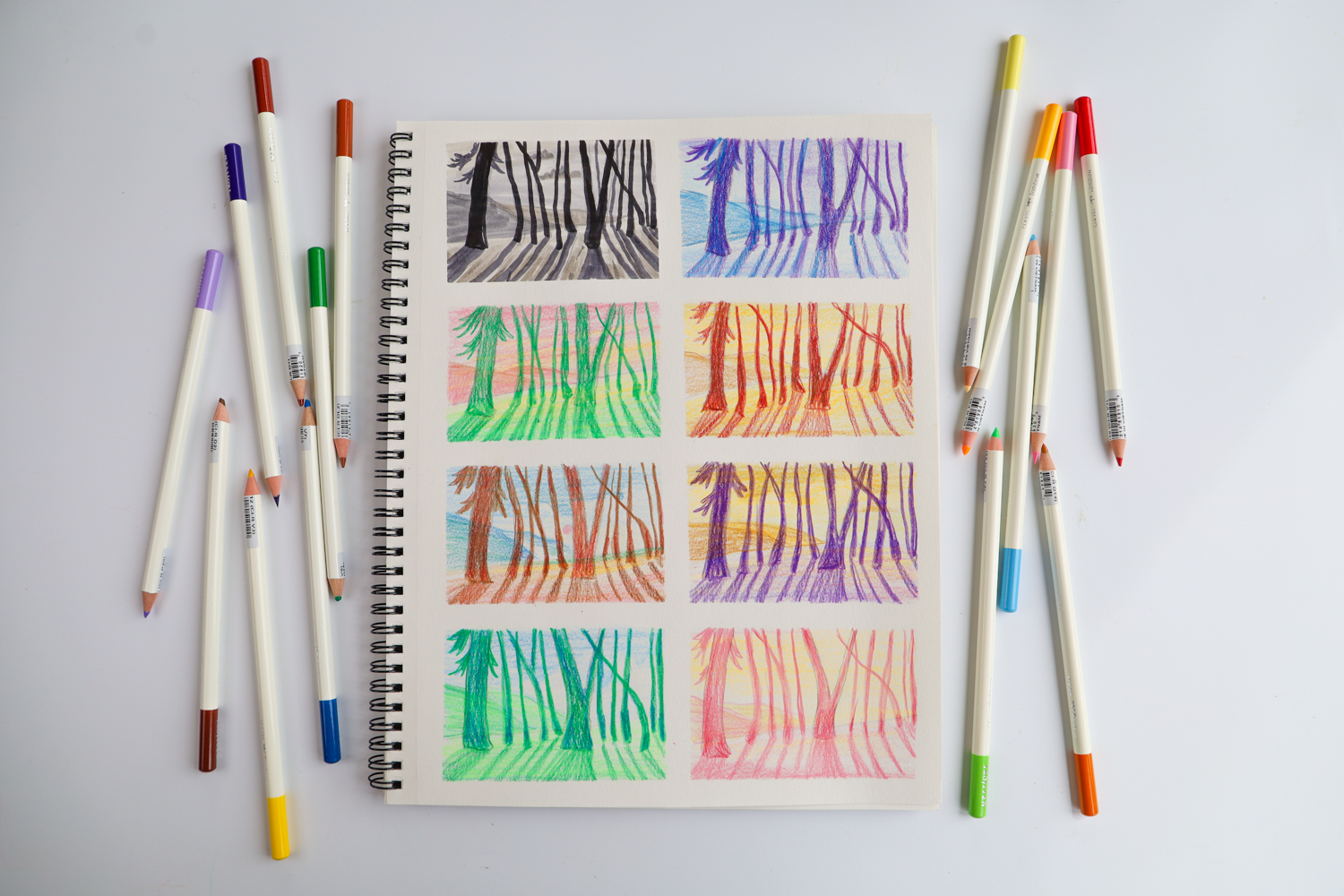 Tombow Irojiten Colored Pencil Desk Cup, Cottage, laying next to a sketchbook filled with color studies of a forest illustration