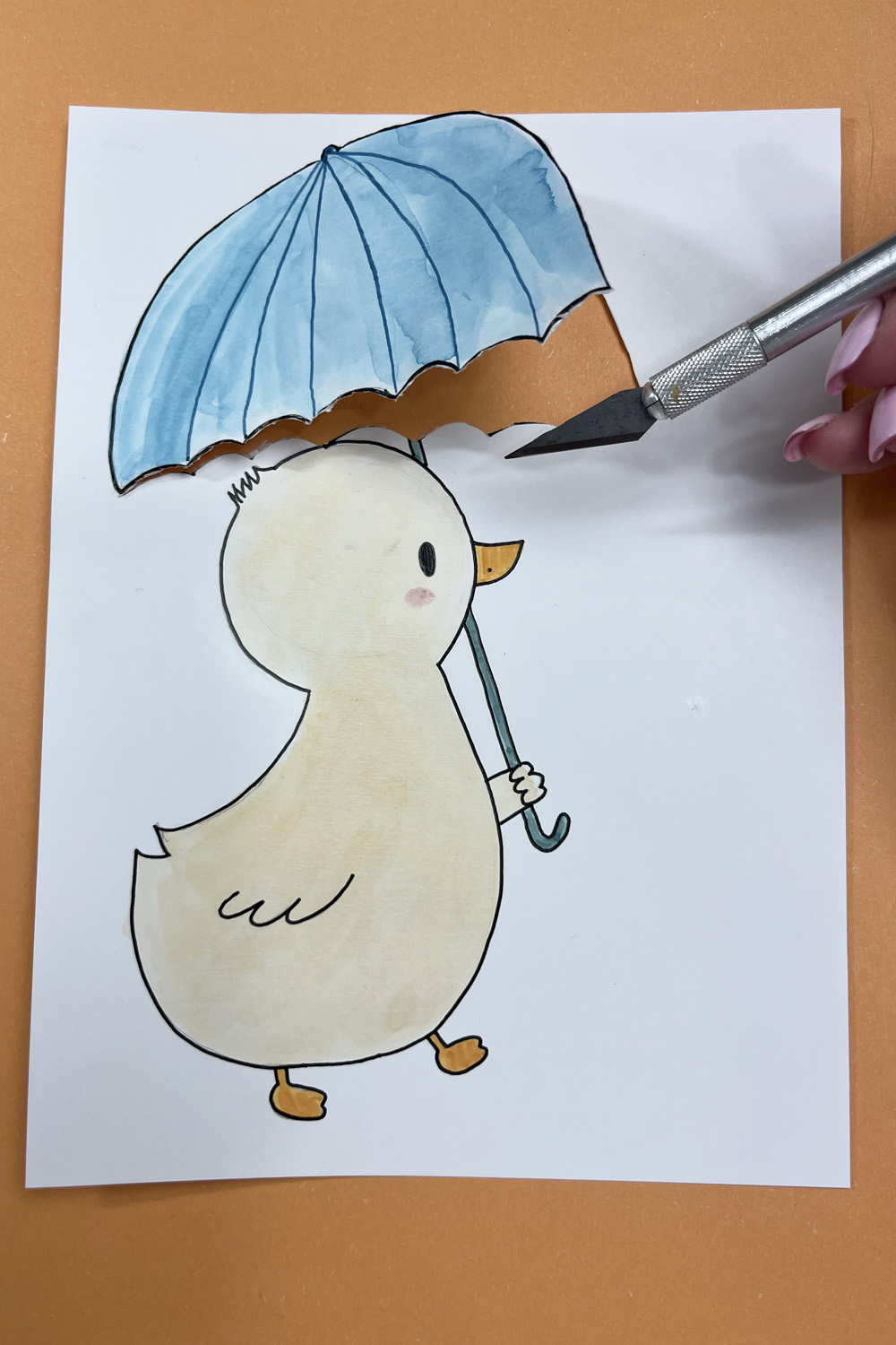 xacto knife cutting out umbrella window on duck drawing